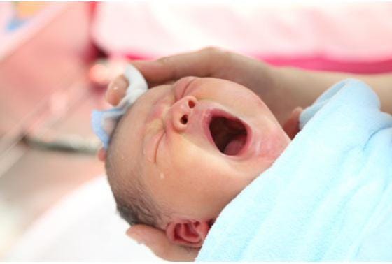 Dùng khăn bông lau khô đầu cho bé trước khi tắm tiếp.
