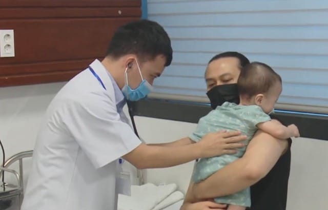 Bác sĩ kiểm tra hô hấp cho trẻ mắc cúm A tại bệnh viện nhi trong mùa dịch.